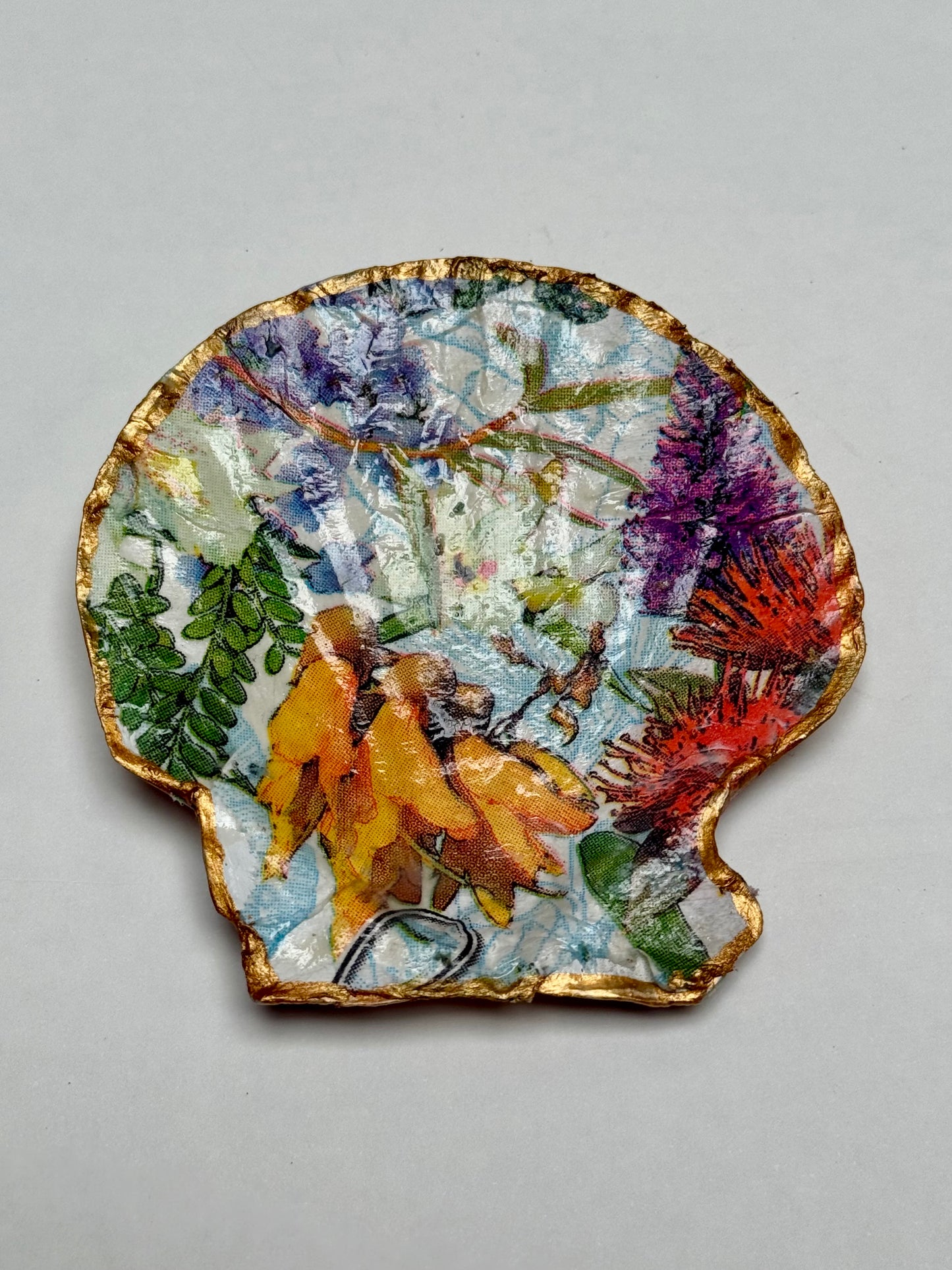 Decoupaged shell with nature-themed design on a gray background