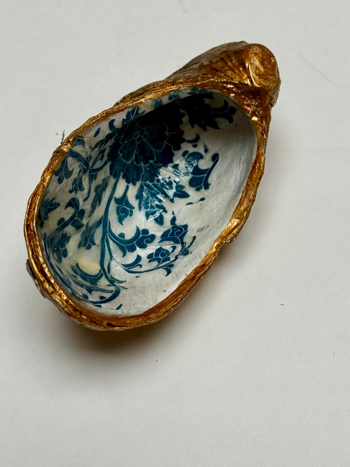 Decorative shell with blue floral patterns and gold rim on a white background