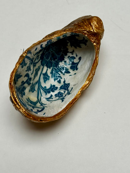 Decorative shell with blue floral patterns and gold rim on a white background